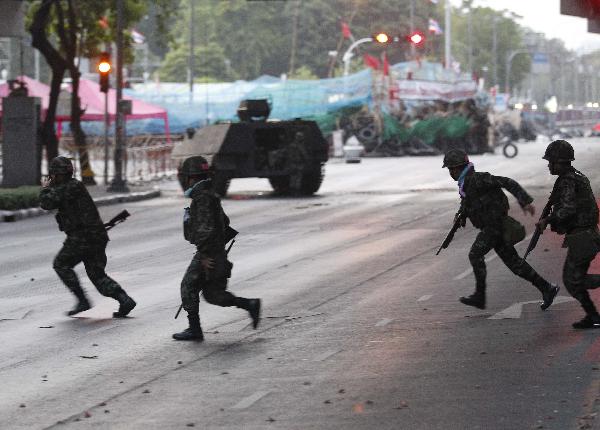 Thai troops and an armoured vehicle take up their positions on a deserted road at the entrance of the business district during a rally by anti-government 'red shirt' protesters in Bangkok May 19, 2010. [Xinhua] 
