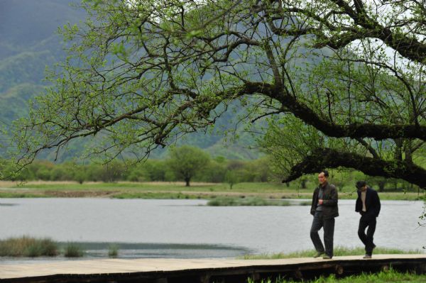 People walk along the bank of a lake in the Dajiuhu Wetland Park in Shennongjia, central China&apos;s Hubei Province, May 18, 2010.[Xinhua/Du Huaju]