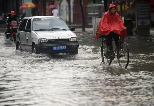 Vehicles wade through a flooded road in Nanchang, capital of Jiangxi province, on May 18, 2010. [Xinhua]
