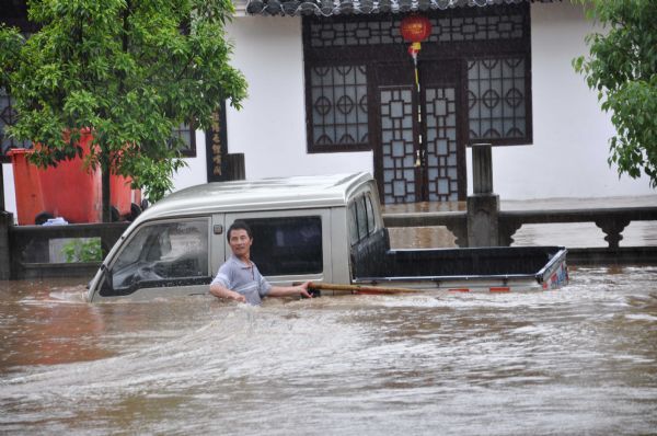 A man and his panel truck are submerged in flood in Wuyuan County, east China&apos;s Jiangxi Province, May 18, 2010. A heavy rainfall hit the county on May 17 and 18. More than 9,300 people have been evacuated.[Xinhua]