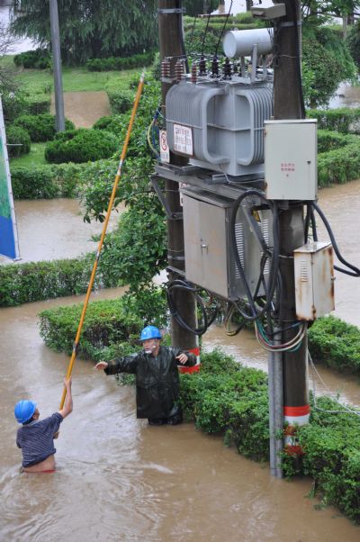 Two power workers try to cut off the power in Wuyuan County, Jiangxi Province, May 18, 2010. A heavy rainfall hit the county on May 17 and 18. More than 9,300 people have been evacuated.