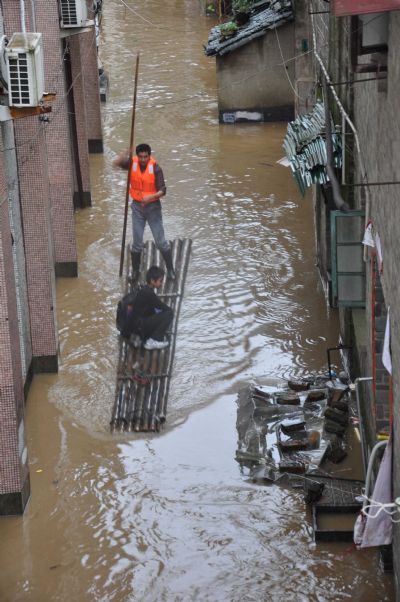 A rescuer evacuates a boy on a flooded road in Wuyuan County, Jiangxi Province, May 18, 2010. A heavy rainfall hit the county on May 17 and 18. More than 9,300 people have been evacuated. 