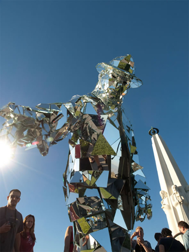 A silver Mirror Man cladded with 1,000 fragments of glass appears in front of the Griffith Observatory of Los Angeles, US, May 19, 2010. 