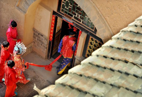 Performers participate in a simulated wedding ceremony at a patio-style courtyard at a cave-house in Shanxian County in central China's Henan Province, May 19, 2010. The local government has established folk museum and tourist village for better conservation and development of the cave dwellings, an intangible cultural relics in Henan Province. [Xinhua]