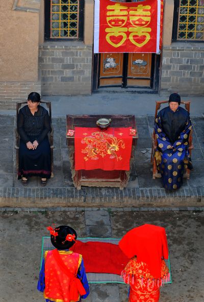 Performers participate in a simulated wedding ceremony at a patio-style courtyard at a cave-house in Shanxian County in central China's Henan Province, May 19, 2010. The local government has established folk museum and tourist village for better conservation and development of the cave dwellings, an intangible cultural relics in Henan Province. [Xinhua]