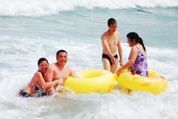 Tourists enjoy themselves in the sea, in Sanya, a popular seaside resort on the southern tip of south China's Hainan Province, May 19, 2010. Local meteorologic bureau issued extremely hot weather alert that parts of the regions of the island, including the provincial capital of Haikou, would be hit by the hot wave, with the peak temperature at 38 degree Celsius. [Xinhua/Jiang Tieying]