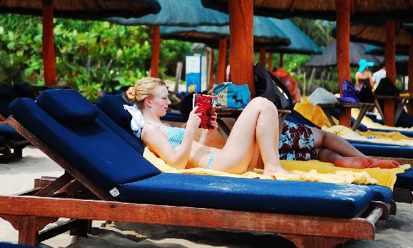 A Russian tourist reads a book in Sanya, a popular seaside resort on the southern tip of south China's Hainan Province, May 19, 2010. Local meteorologic bureau issued extremely hot weather alert that parts of the regions of the island, including the provincial capital of Haikou, would be hit by the hot wave, with the peak temperature at 38 degree Celsius. [Xinhua/Jiang Tieying] 