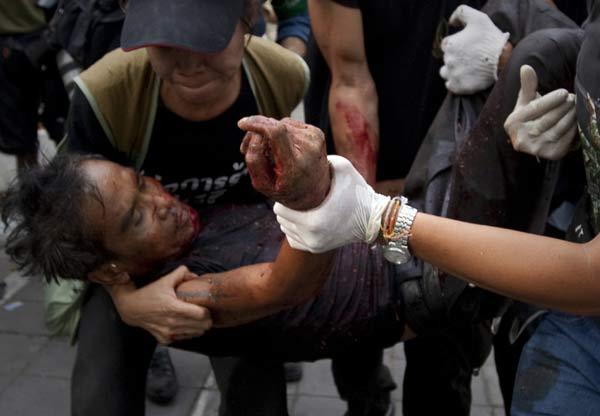 Anti-government supporters rush a fellow &apos;red shirt&apos; to safety after he was shot by army soldiers who were penetrating the &apos;red shirt&apos; encampment in Bangkok May 19, 2010. 