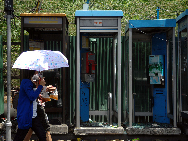 Local residents pass by destroyed telephone booth in Bangkok, May 21, 2010.[Xinhua]