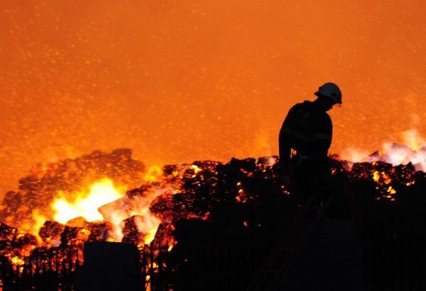 A fireman works near a flaming workshop in Hengxian County of Nanning city, capital of southwest China&apos;s Guangxi Zhuang Autonomous Region, on May 21, 2010. A workshop containing bagasse in Nanning caught fire on Friday, causing no casauties. [Xinhua]