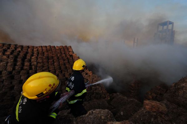 Firemen work near a flaming workshop in Hengxian County of Nanning city, capital of southwest China&apos;s Guangxi Zhuang Autonomous Region, on May 21, 2010. A workshop containing bagasse in Nanning caught fire on Friday, causing no casauties. [Xinhua]