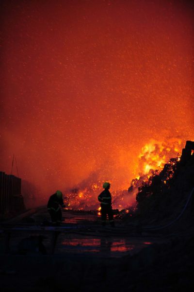 Firemen work near a flaming workshop in Hengxian County of Nanning city, capital of southwest China&apos;s Guangxi Zhuang Autonomous Region, on May 21, 2010. A workshop containing bagasse in Nanning caught fire on Friday, causing no casauties. [Xinhua]