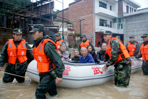 Police officers help transfer local residents out of the flood-plagued city of Xinyu, East China&apos;s Jiangxi province, May 21, 2010. More than 9,000 people were evacuated after the 5th rainstorm in less than a month hit the city, tearing down houses and flooding farmlands. [Xinhua]