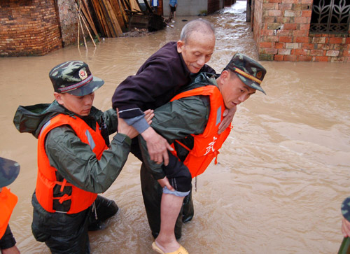 Police officers carry an old man out of a flood-soaked area in Xinyu, East China&apos;s Jiangxi province, May 21, 2010. [Xinhua] 