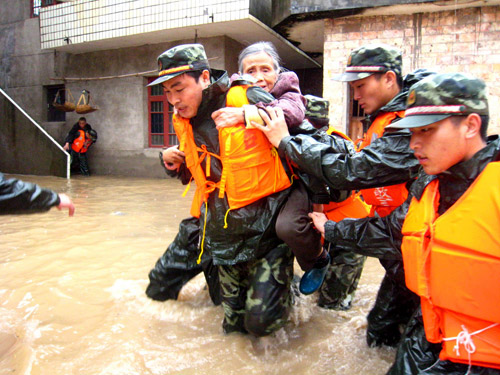 Police officiers help an old woman evacuate from a flood-soaked area in Xinyu, East China&apos;s Jiangxi province, May 21, 2010. [Xinhua] 