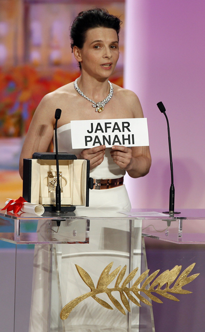 Actress Juliette Binoche holds up a poster reading the name of Iranian jury member Jafar Panahi imprisoned as she received the Best Actress prize for her role in Iranian director Abbas Kiarostami's film Copie Conforme (Certified Copy) during the award ceremony of the 63rd Cannes Film Festival May 23, 2010.