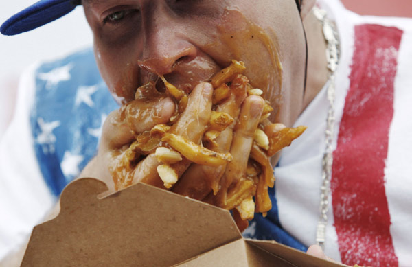 Pete &apos;Pretty Boy&apos; Davekos takes part in the &apos;World Poutine Eating Championship&apos; in Toronto, May 22, 2010. Contestants had 10 minutes to eat as much poutine, a dish consisting of french fries, cheese curds, and brown gravy, to win the championship. [Xinhua/Reuters]