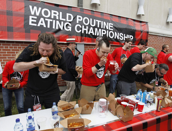 Contestants takes part in the &apos;World Poutine Eating Championship&apos; in Toronto, May 22, 2010. Contestants had 10 minutes to eat as much poutine, a dish consisting of french fries, cheese curds, and brown gravy, to win the championship. [Xinhua/Reuters] 