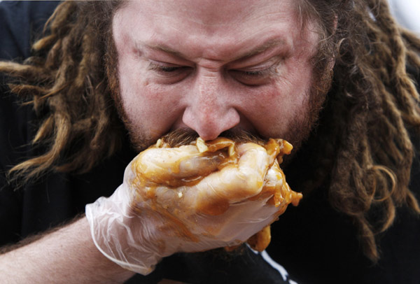 &apos;Crazy Legs&apos; Conti takes part in the &apos;World Poutine Eating Championship&apos; in Toronto, May 22, 2010. Contestants had 10 minutes to eat as much poutine, a dish consisting of french fries, cheese curds, and brown gravy, to win the championship. [Xinhua/Reuters]