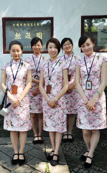 New tour guides, wearing Chinese traditional chi-paos, stand at the Zhuozhengyuan Garden of Suzhou, east China's Jiangsu Province, May 24, 2010. A total of 13 new tour guides, who would offer free explanations for tourists, began to work at the garden Monday. (Xinhua/Zhu Guigen)