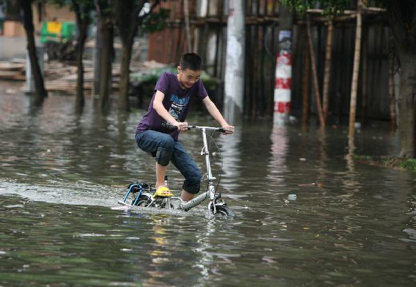 A young man rides on a flooded street in Quanzhou City, southeast China's Fujian Province, May 23, 2010. Heavy rain hit the province on May 22 and 23. [Xinhua] 