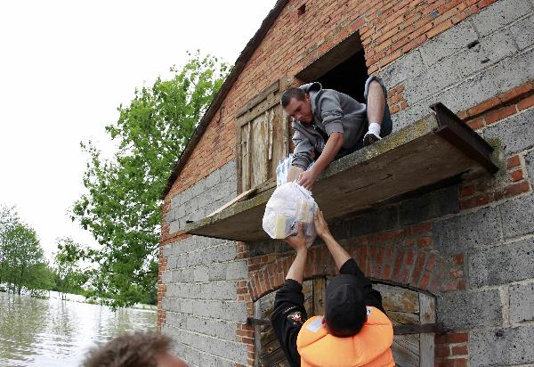 An emergency worker gives food suplies to a man in a flooded house in the village of Juliszew close to Plock in Central Poland May 24, 2010. [Xinhua/Reuters]