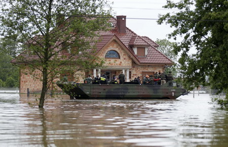 An amphibious vehicle transports people from the flooded village of Juliszew, close to Plock, central Poland, May 24, 2010.[China Daily/Agencies]