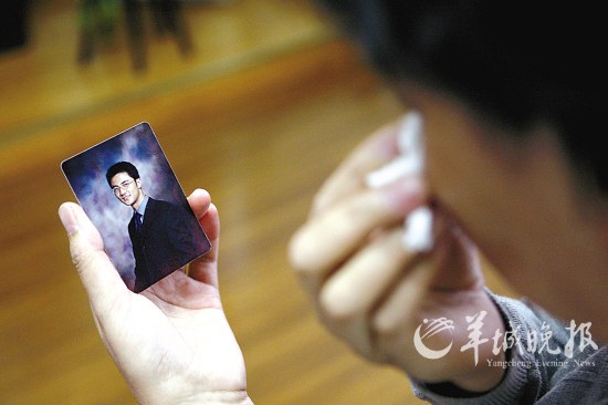 Zhai Tiantian's mother, Wang Xiaojun, sheds tears while she looks at a photo of her son on Saturday at her home in Xi'an, Shaanxi province. [Yangcheng Evening News]