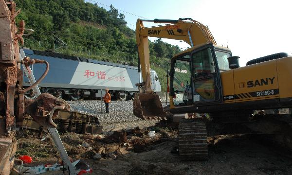 A train passes by workers who are cleaning muds and rocks at a section of the Shanghai-Kunming railway line in Dongxiang County, east China's Jiangxi Province, May 24, 2010. 