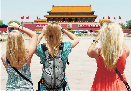 Three foreign tourists take photos on Tian'anmen square on Tuesday. wang jing / China Daily 