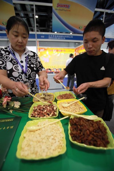 Visitors taste some nuts and dried fruit during the 2010 China Beijing International Snack Food Exhibition held in Beijing, May 25, 2010. A total of 181 enterprises from 14 countries and regions took part in the exhibition that opened on Tuesday. 