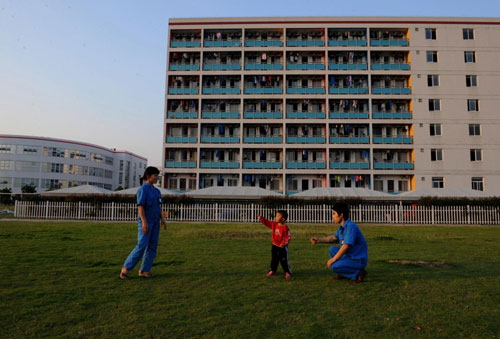 The couple play with their 2-year-old boy on a lawn of the factory after work in Hangzhou, East China's Zhejiang province, May 25, 2010. 