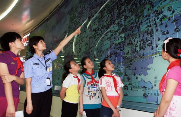 A policeman introduces prevention and control information to pupils of Dongjiaominxiang Primary School during a thematic activity at Beijing '110' police commanding center in Beijing, capital of China, May 25, 2010. Policeman of the '110' commanding center communicated with students and explained safety knowledge to them during the activity on Tuesday.