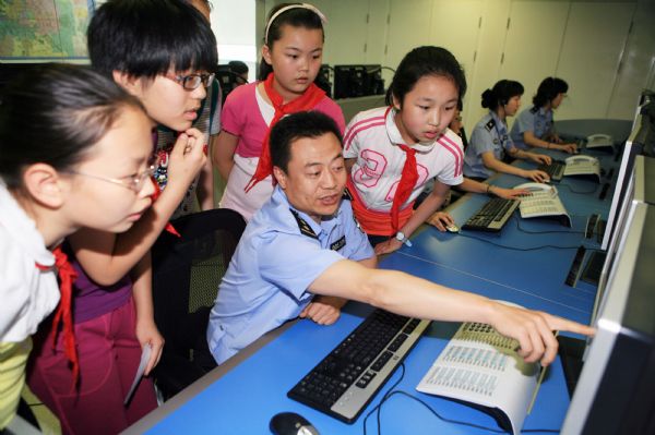 A policeman introduces working process of the alarm information desk to pupils of Dongjiaominxiang Primary School during a thematic activity at Beijing '110' police commanding center in Beijing, capital of China, May 25, 2010. Policeman of the '110' commanding center communicated with students and explained safety knowledge to them during the activity on Tuesday.