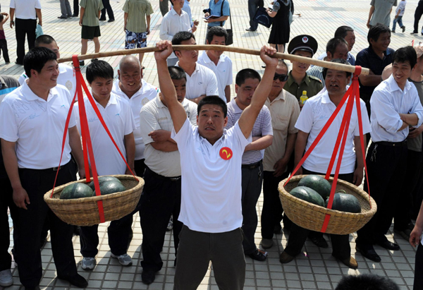 A farmer competes in the weightlifting game at the watermelon festival in Zhongmu county of Zhengzhou city, capital of Central China's Henan province, May 25, 2010. Watermelon sellers and farmers in Zhongmu displayed their high-quality fruit Tuesday by competing in eating and lifting melons as well as honoring the master grower at the festival. 