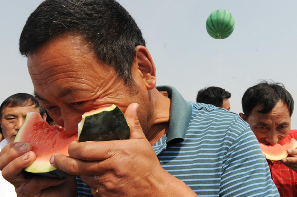 A farmer competes in the eating game at the watermelon festival in Zhongmu county of Zhengzhou city, capital of Central China's Henan province, May 25, 2010.