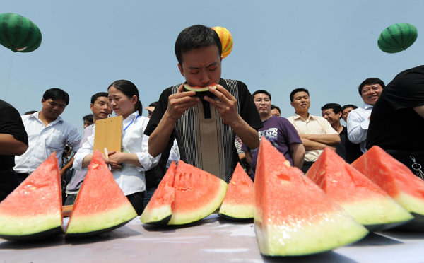 A farmer competes in the eating game at the watermelon festival in Zhongmu county of Zhengzhou city, capital of Central China's Henan province, May 25, 2010.