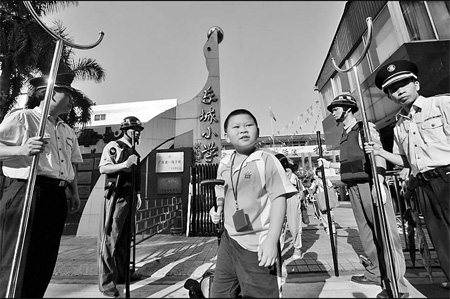 Students of a primary school in Panyu of Guangzhou, Guangdong province, exit the campus gate guarded by a number of security personnel.