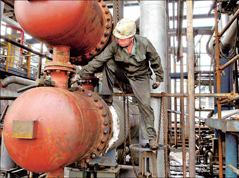 A Sinopec employee inspects equipment in Qingjiang, Jiangsu province. Oil refining capacity of foreign companies in China will rise to 31.5 million tons per year by 2015. [China Daily]