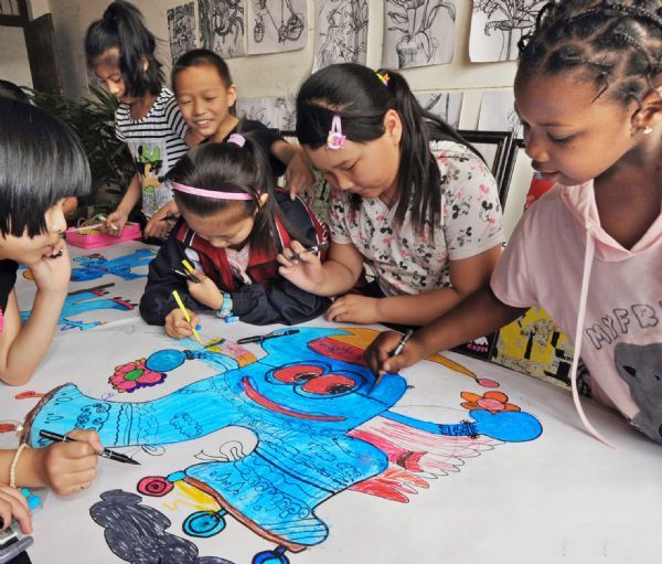 Kichh (1st, R) and his classmates draw a picture of Haibao, the mascot of the World Expo 2010 Shanghai, in Yiwu, east China&apos;s Zhejiang Province, May 27, 2010. Muhammed, 11 years old, and his sister Kichh, 8 years old, came to Yiwu 5 years ago with their parents who run businesses here. They entered a local school successively in 2007 and 2008, and they are very fond of Chinese culture. [Xinhua]