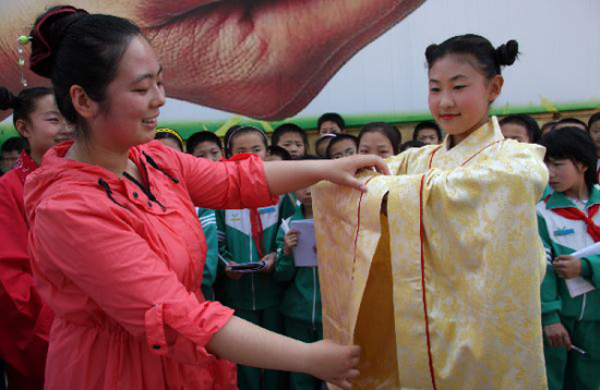 Professional Ye Han (L) teaches traditional comity to students at the Yifu Primary School in Zaozhuang, east China's Shandong Province, May 25, 2010. The primary school invited professionals to introduce the culture of ancient costumes of Han ethnic group to students on Tuesday. [Xinhua photo]
