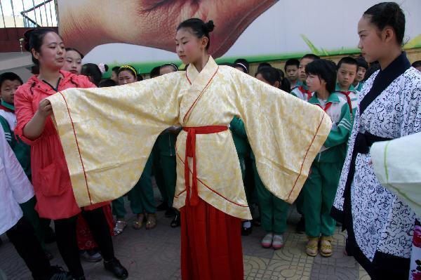 Professional Ye Han (L in front) explains culture of ancient costumes of Han ethnic group to students at the Yifu Primary School in Zaozhuang, east China's Shandong Province, May 25, 2010. The primary school invited professionals to introduce the culture of ancient costumes of Han ethnic group to students on Tuesday. (Xinhua/Sun Zhongzhe) 