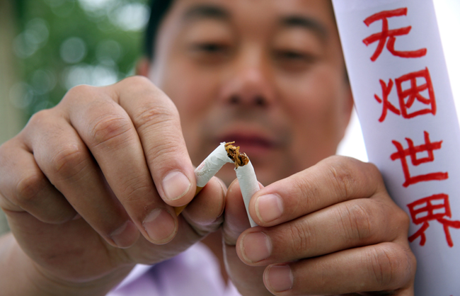 A parent breaks a cigarette to show his determination to quit smoking at Hongqi Primary School in Zaozhuang City, east China&apos;s Shandong Province, May 27, 2010. With the coming of the World No-Tobacco Day on May 31, students in Zaozhuang City launched a no-tobacco compaign recently to advocate the life style of no tobacco and low-carbon health. [Xinhua] 