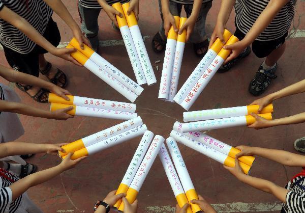 Pupils show cigarette models on which they wrote many slogans to call upon people to quit smoking, at Hongqi Primary School in Zaozhuang City, east China&apos;s Shandong Province, May 27, 2010. With the coming of the World No-Tobacco Day on May 31, students in Zaozhuang City launched a no-tobacco compaign recently to advocate the life style of no tobacco and low-carbon health. [Xinhua]