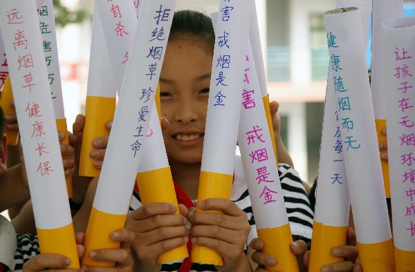 A girl holds cigarette models on which students wrote many slogans to call upon people to quit smoking, at Hongqi Primary School in Zaozhuang City, east China&apos;s Shandong Province, May 27, 2010. With the coming of the World No-Tobacco Day on May 31, students in Zaozhuang City launched a no-tobacco compaign recently to advocate the life style of no tobacco and low-carbon health. [Xinhua]