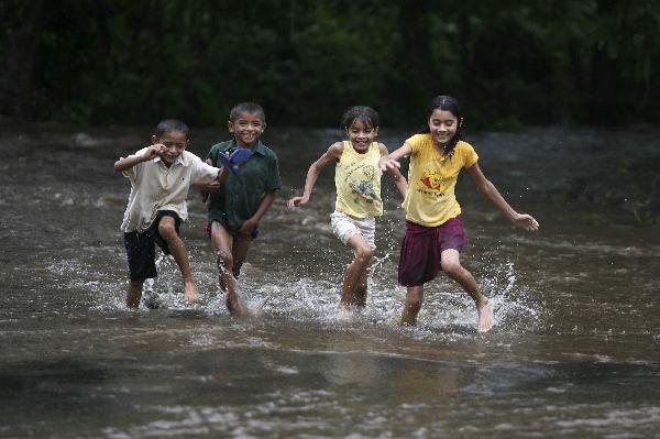 Children play flooded town, 135 km west Children play on a river flooded by heavy rain in Quezalguaque town, some 135 km (110 miles) west of the capital Managua, May 27, 2010. [Xinhua/Reuters]