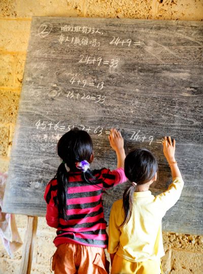 Two pupils answer questions in front of the blackboard in Naliang Village of Qiangxu Township, Dahua Yao Autonomous County of southwest China's Guangxi Zhuang Autonomous Region, May 17, 2010. 