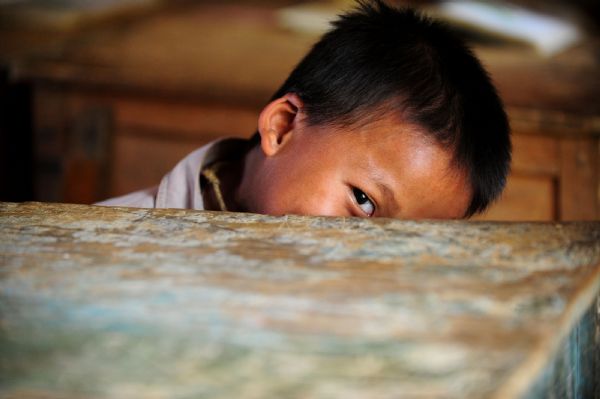 Meng yousheng of the first grade hides himself in the classroom in Naliang Village of Qiangxu Township, Dahua Yao Autonomous County of southwest China's Guangxi Zhuang Autonomous Region, May 17, 2010. 