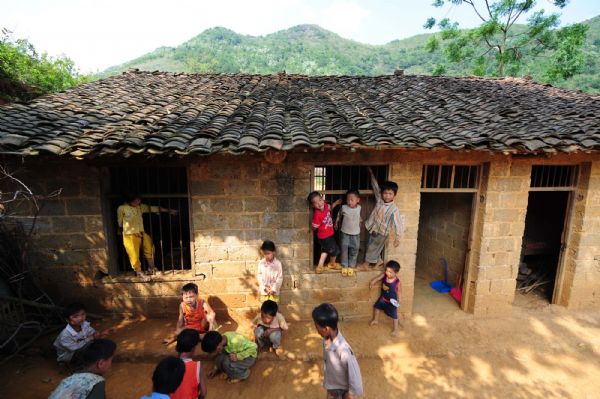 Pupils play outside the classroom in Naliang Village of Qiangxu Township, Dahua Yao Autonomous County of southwest China's Guangxi Zhuang Autonomous Region, May 17, 2010. 