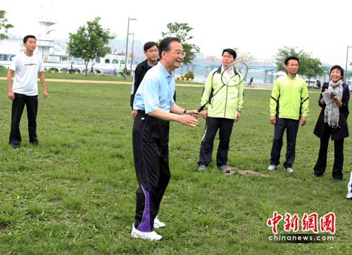 Chinese Premier Wen Jiabao plays badminton with one of the local residents as he joins them in morning exercises in Seoul, May 29, 2010. [Zhou Zhaojun/Chinanews.com]